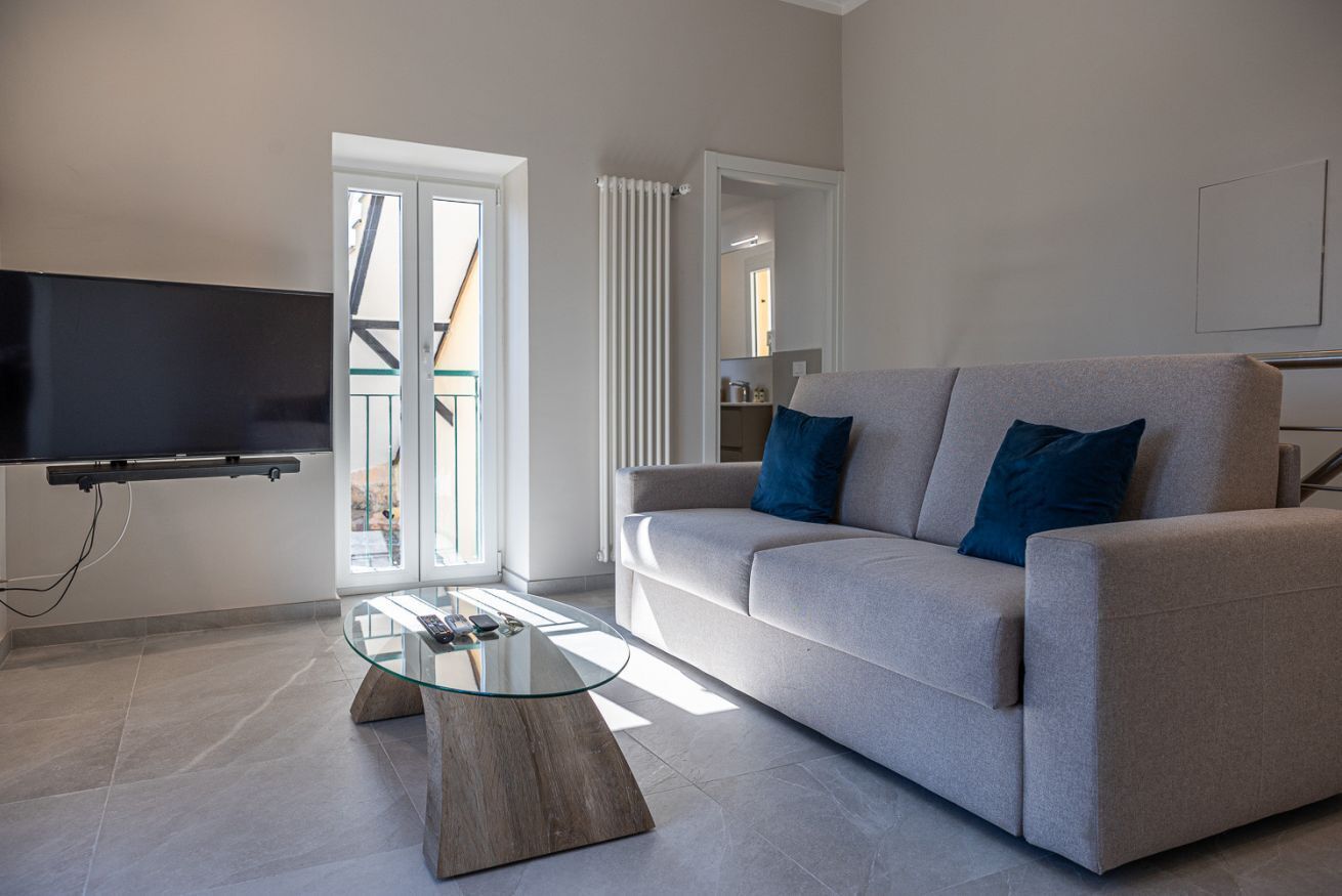 En moderne stue med sofa, sofabord i glas, fladskærms-TV og en skydedør i glas.