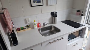 A modern kitchen with white cabinets, a stainless steel sink, and a black induction cooktop.