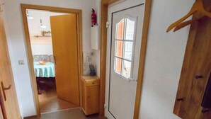 A narrow hallway with wooden cabinets, a small table, and a door with a window. - Geiserich by Interhome (Blankenburg)