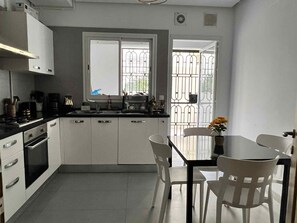 A compact kitchen with white cabinets, a stove, and a sink. There is a window with a view of a metal gate outside. - Luxury apartment 170 m² La Marsa - 3 bedrooms, terrace & private parking (La Marsa)