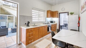 A modern kitchen with wooden cabinets, a white countertop, and a dining area with a marble table. - Traditional, large 3 bedroom house with Yard JBAR1-1 (St Julian's)