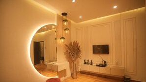Una sala moderna con un espejo redondo, piso de madera, un televisor de pantalla plana y una mesa de centro.