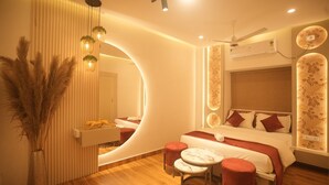 Un dormitorio moderno con un espejo curvo, una cama con ropa de cama roja, una mesita redonda pequeña y una planta decorativa.
