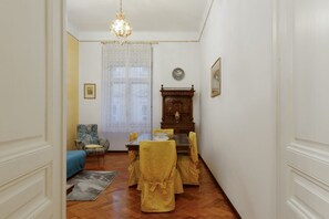 A dining area with a wooden table, yellow chairs, and a chandelier. - Elegant Historic Apartment in Trieste City Centre (Trieste)