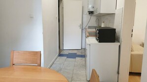 Una cocina compacta con microondas, un refrigerador blanco y una pequeña encimera.