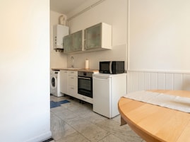 A compact kitchen with a washing machine, a microwave, and a small oven.