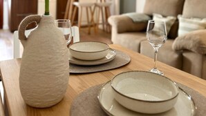 Une table à manger avec des assiettes, un vase et des verres, le tout préparé pour un repas.