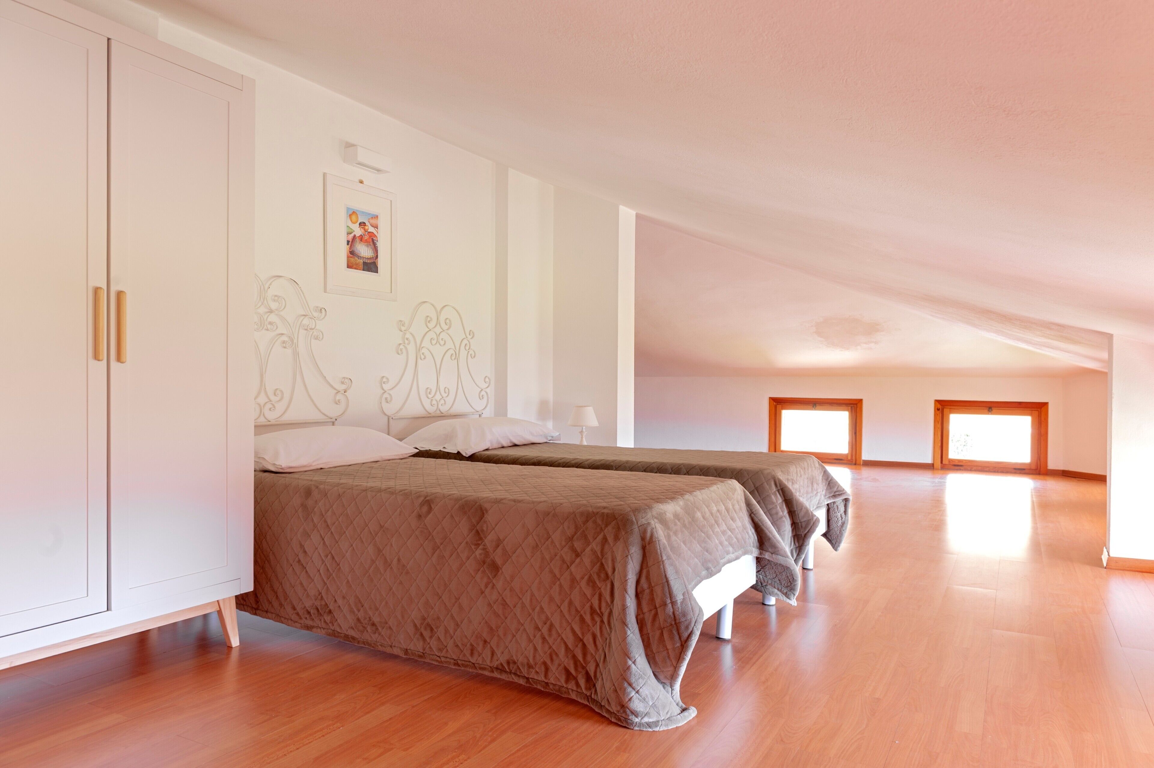 A bedroom with two beds, a wardrobe, and a ceiling with skylights.