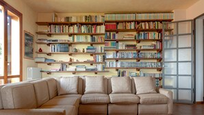 Ein Wohnzimmer mit einer Eckcouch, einem Bücherregal voller Bücher und einer Heizung.