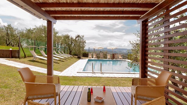 Ein überdachter Außenbereich mit Pool, Liegestühlen und einem Tisch mit Flaschen und Gläsern.