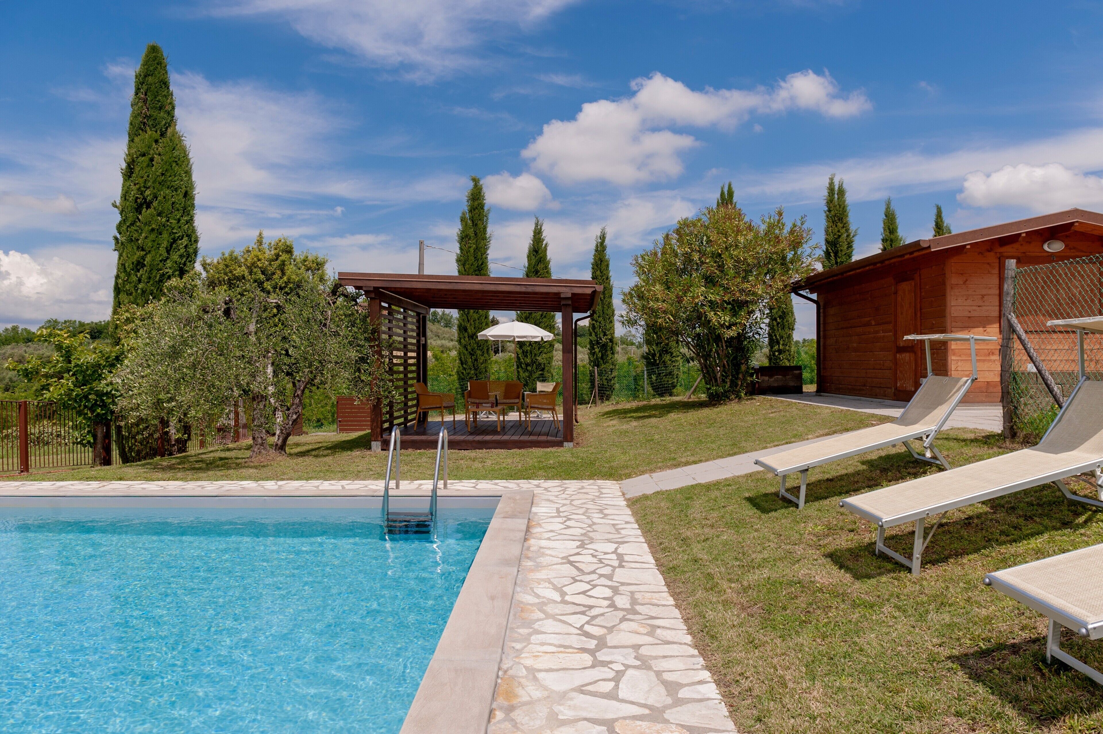 A swimming pool with lounge chairs and a pergola.