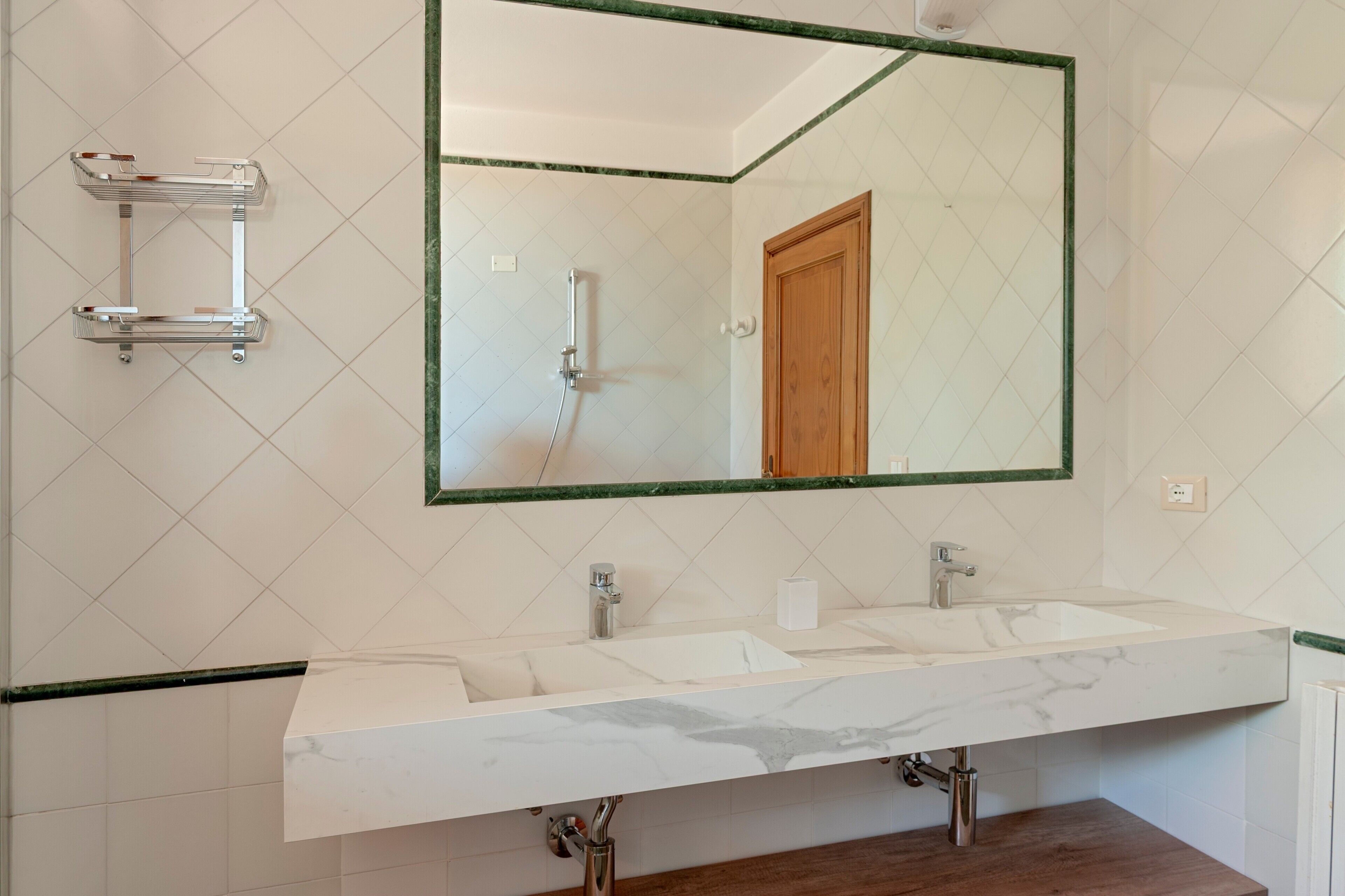 Un baño con un espejo grande, dos lavamanos y una ducha.
