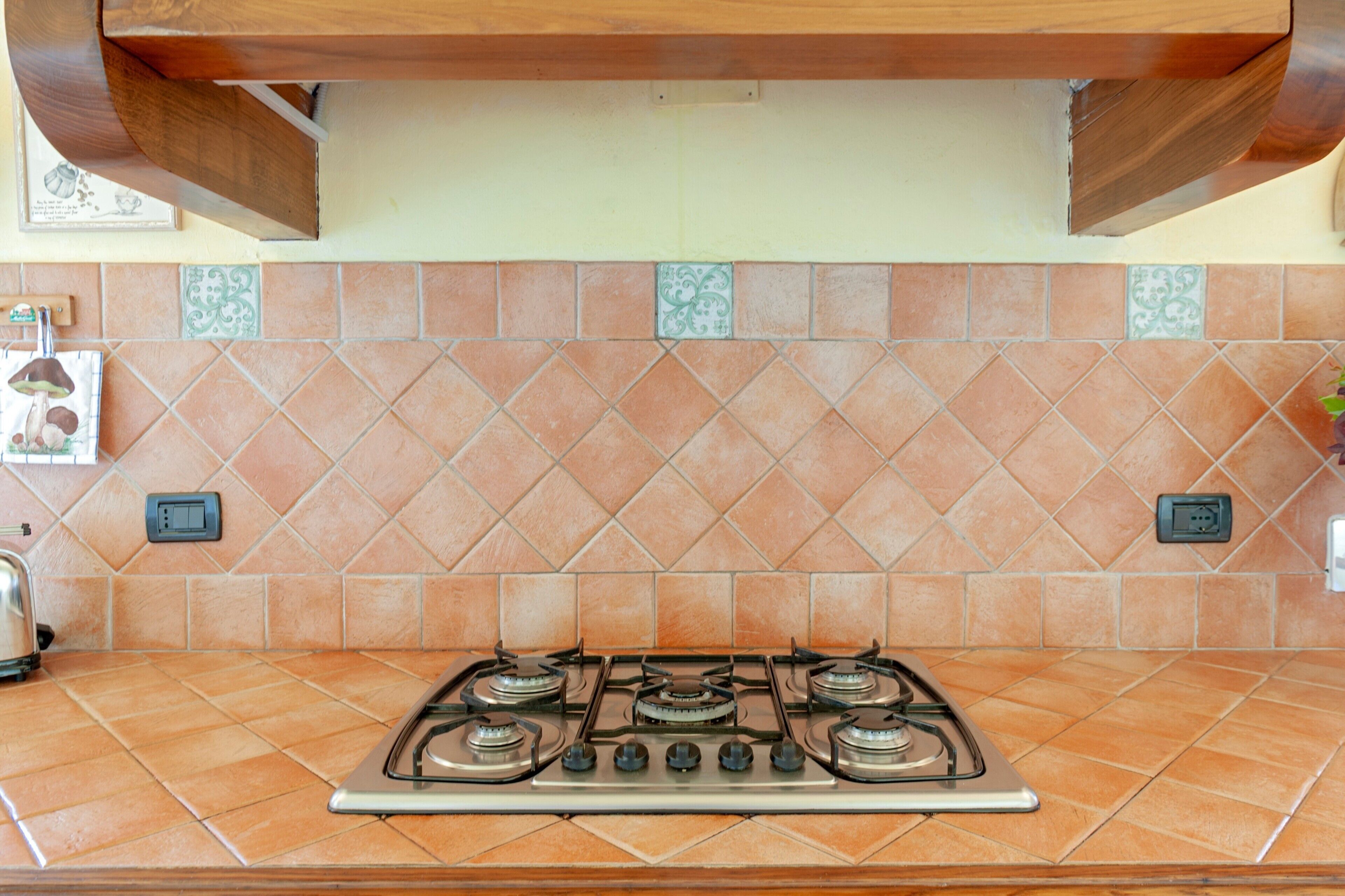 A kitchen with a gas stove, tiled backsplash, and wooden cabinets.