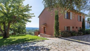 A house with a stone pathway leading to the entrance, surrounded by greenery and a view of the landscape. - Holiday Home 'Appartamento Il Nespolo' with Private Terrace, Wi-Fi & Air Conditioning (Pontedera)