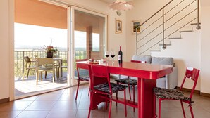 A dining area with a red table and chairs, a balcony with a view, and a staircase. - Holiday Home 'Appartamento Il Nespolo' with Private Terrace, Wi-Fi & Air Conditioning (Pontedera)