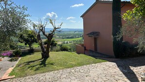 A stone-paved courtyard with a view of a rural landscape, a building with a tiled roof, and a tree. - Holiday Home 'Appartamento Il Nespolo' with Private Terrace, Wi-Fi & Air Conditioning (Pontedera)