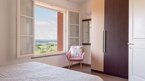 A bedroom with a bed, a chair, a wardrobe, and a window with a view. - Holiday Home 'Appartamento Il Nespolo' with Private Terrace, Wi-Fi & Air Conditioning (Pontedera)