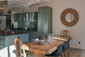 Een moderne keuken met groene kastjes, een houten eettafel en stoelen.