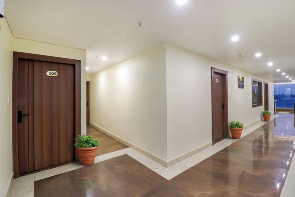 A hallway with doors numbered 306 and 307, potted plants, and a tiled floor. - Hotel RK Residency (Dehradun)