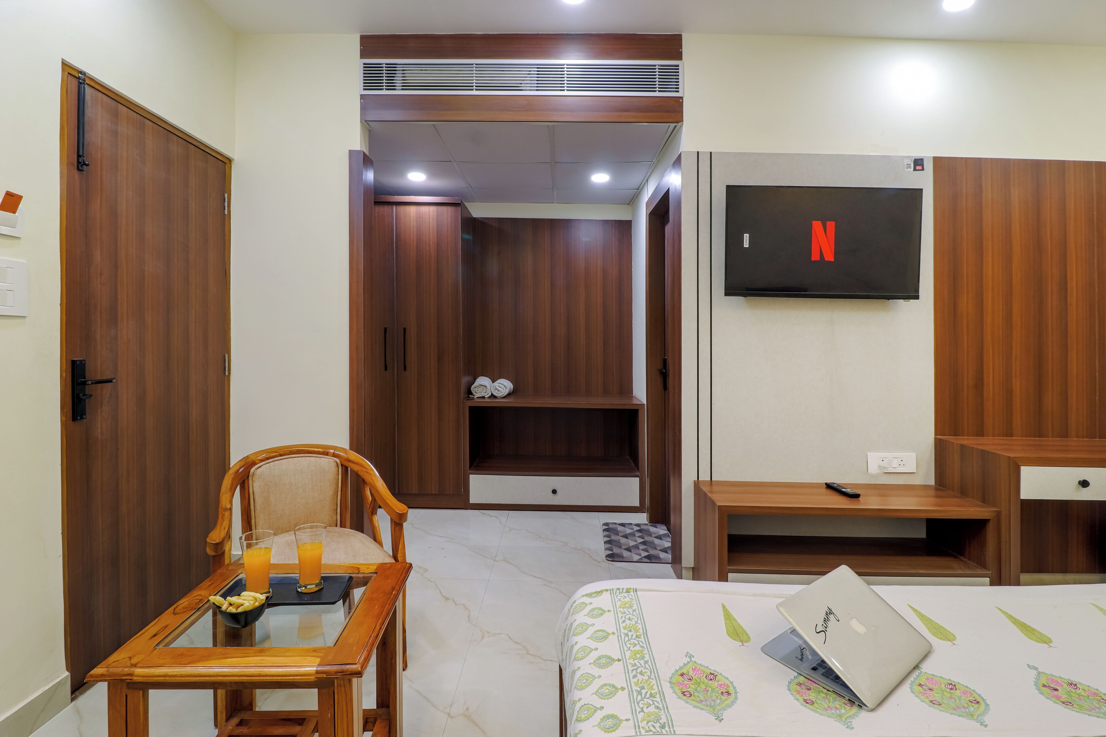 A hotel room with a bed, a desk, a chair, a TV, and a wardrobe.