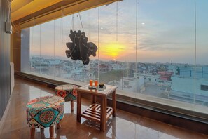 A balcony with a city view, a table with drinks, and a hanging ornament. - Hotel RK Residency (Dehradun)