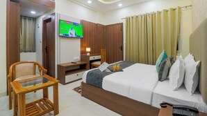 Una habitación de hotel con cama, escritorio, televisor, silla y teléfono.