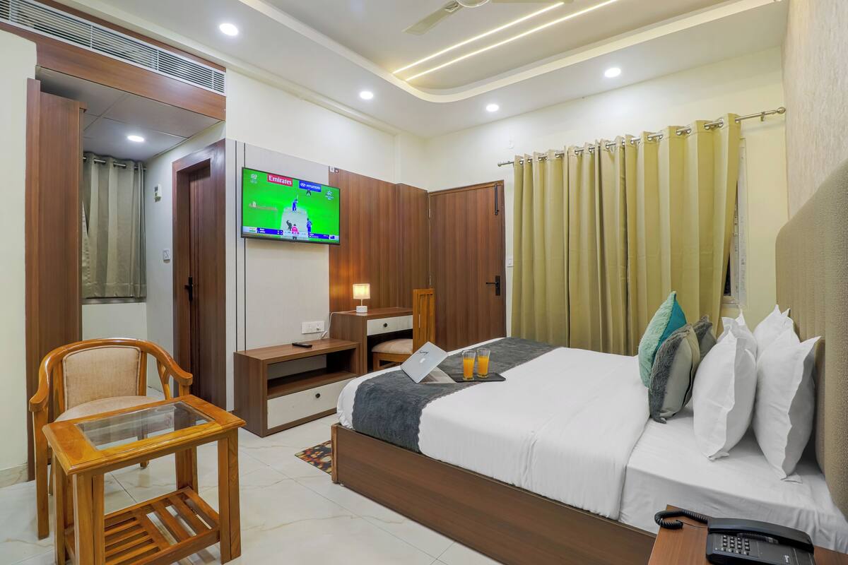 A hotel room with a bed, a desk, a TV, a chair, and a telephone.