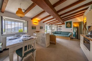 A kitchen with a dining area, wooden beams, a view through a window, and a sofa. -  VILLA SANTINCIELO - Relax between sky and sea (Rapallo)