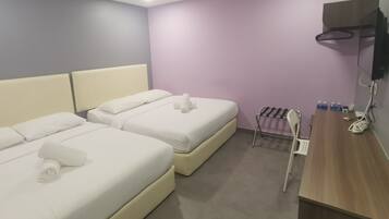 A hotel room with two beds, a wooden desk, a TV mounted on the wall, and a small seating area with a chair and a rack holding bottles.