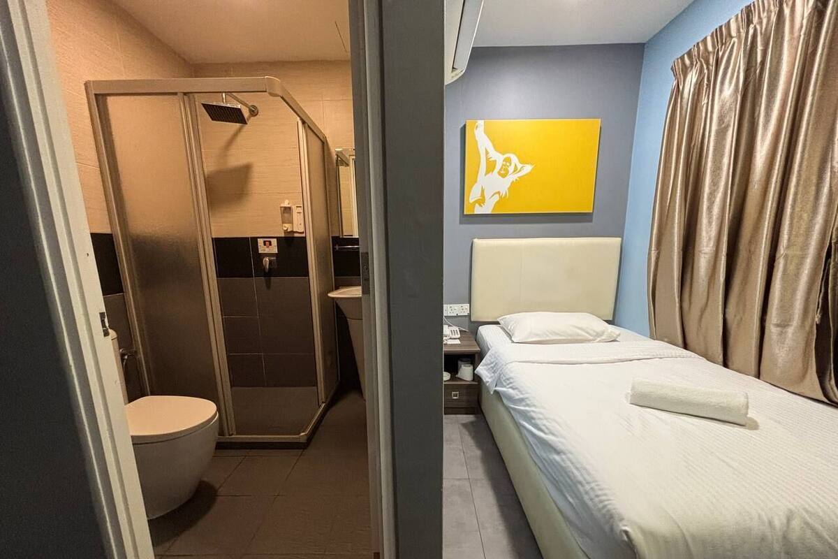 Ein Hotelzimmer mit Dusche, Toilette und einem Bett mit Kissen und Handtuch.