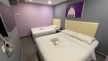 Ein Hotelzimmer mit zwei Betten, jeweils mit Kopfteil und Kissen. An der Wand ist ein Fernseher befestigt und ein Gemälde eines Gebäudes hängt dort.
