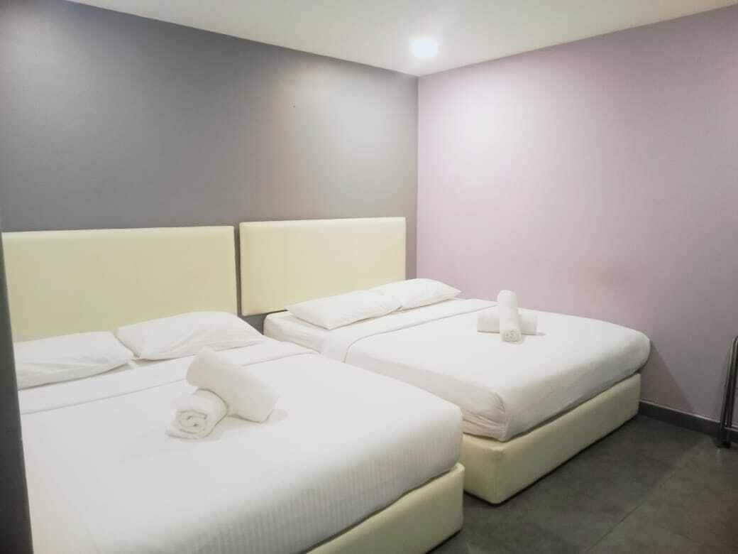 Ein Hotelzimmer mit zwei Betten, jeweils mit weißer Bettwäsche und Kissen, und einem kleinen Handtuch auf den Betten.