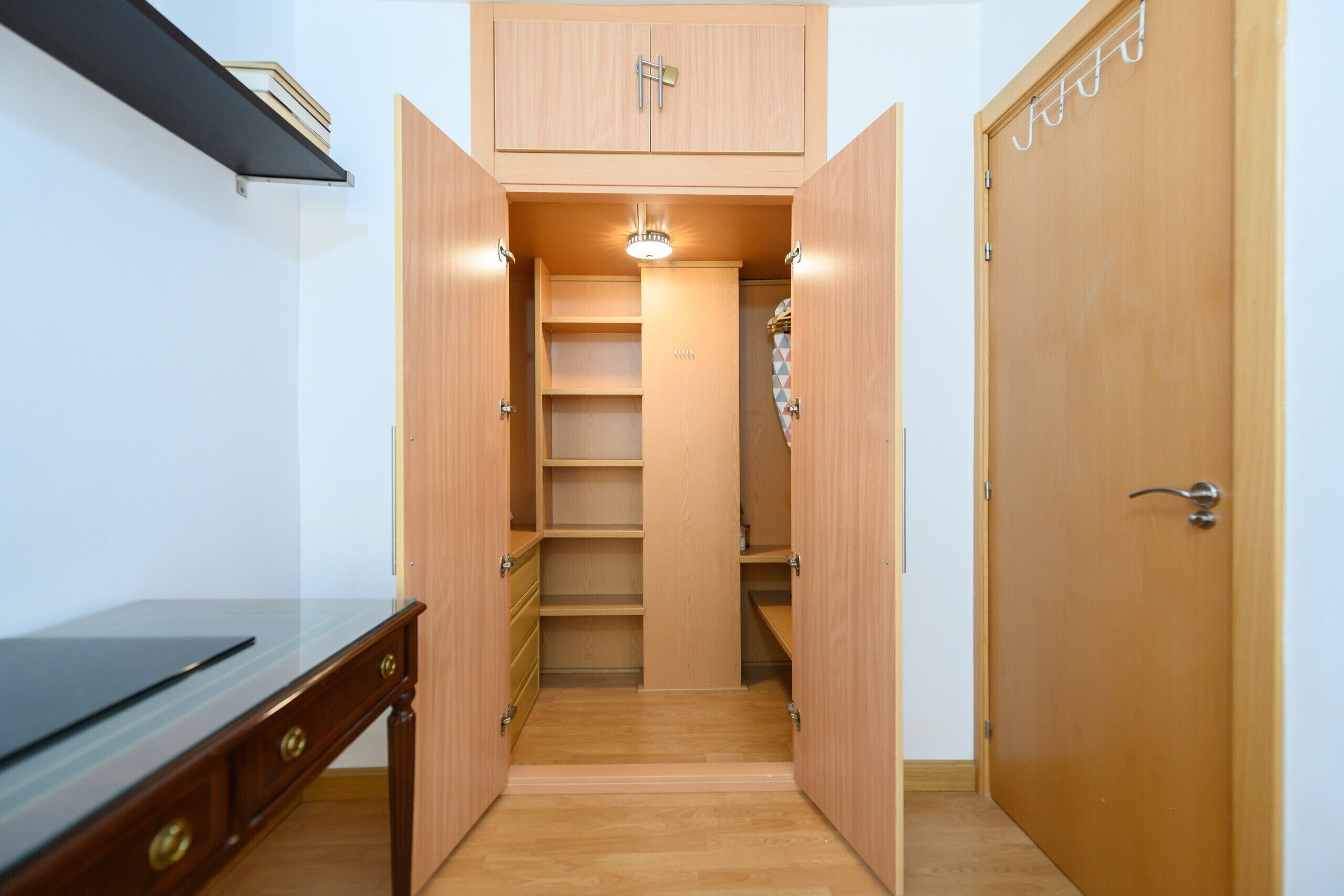 Ein Zimmer mit einem Holztisch, einem Kleiderschrank und einer eingebauten Regalanlage.