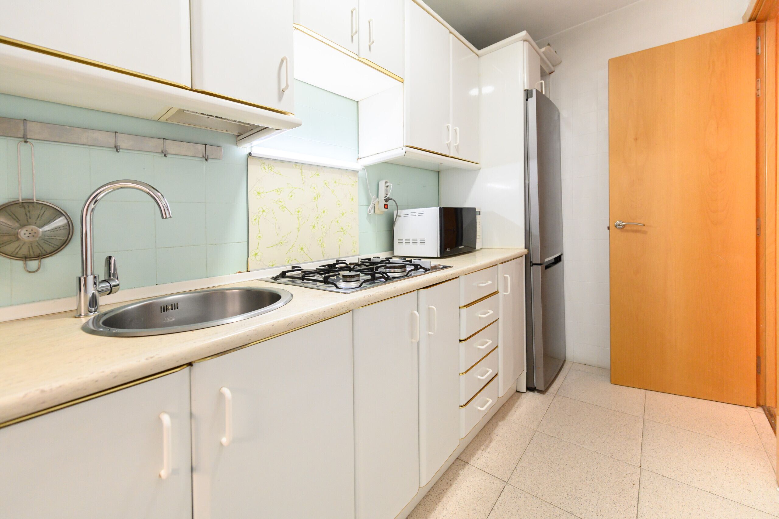 Una cocina equipada con fregadero, estufa, microondas y refrigerador.