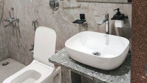 Un bagno moderno con un water bianco, un lavandino ampio e uno specchio sopra il lavandino.