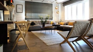 Una sala de estar moderna con sofá, mesa de centro y zona de comedor con sillas.