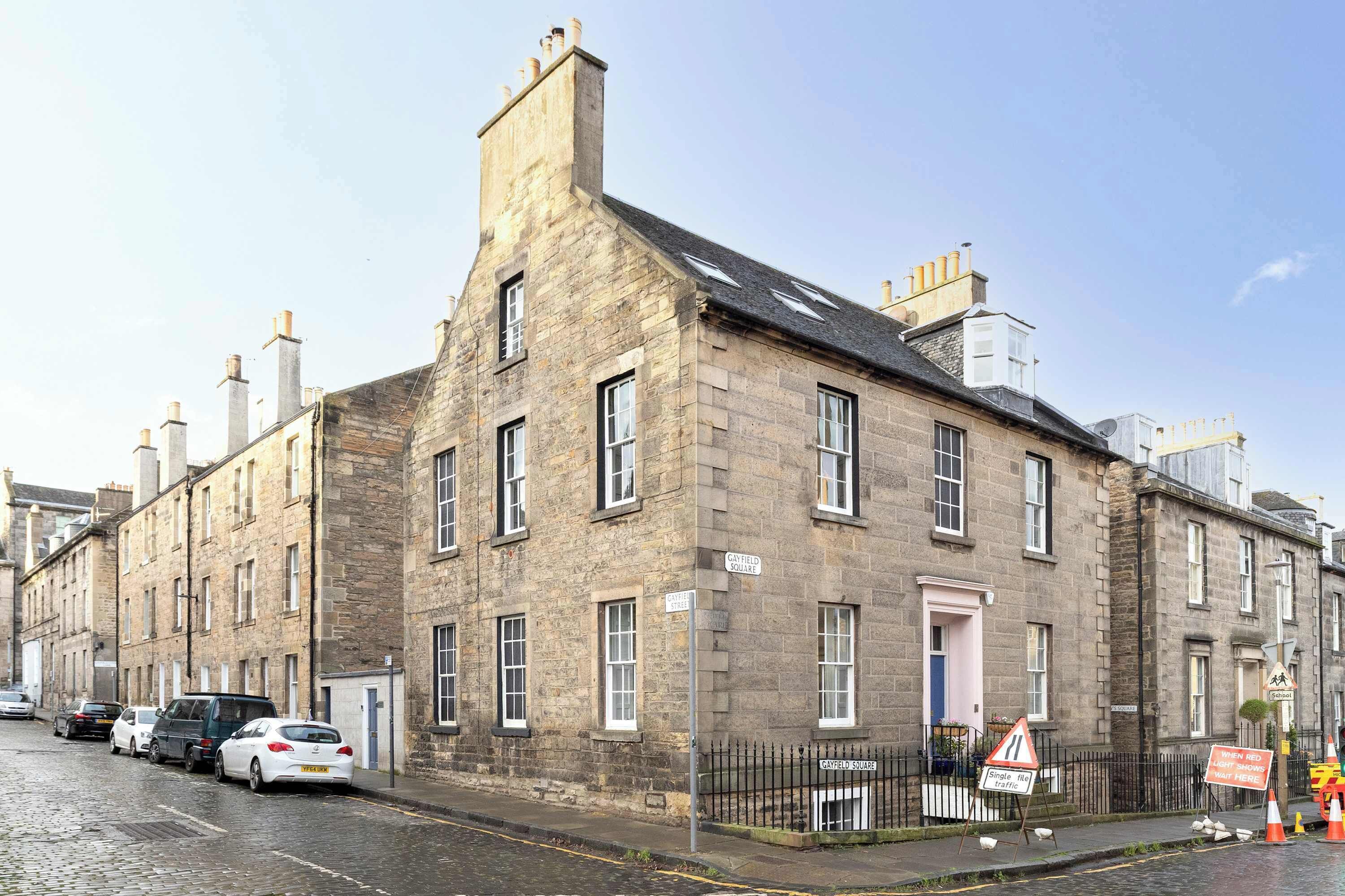 A historic stone building with multiple windows and a sign indicating 'Cranfield Square'.