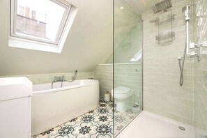 A modern bathroom with a bathtub, toilet, and glass-enclosed shower area. - Luxury Family Flat in Edinburgh New Town (Edinburgh)