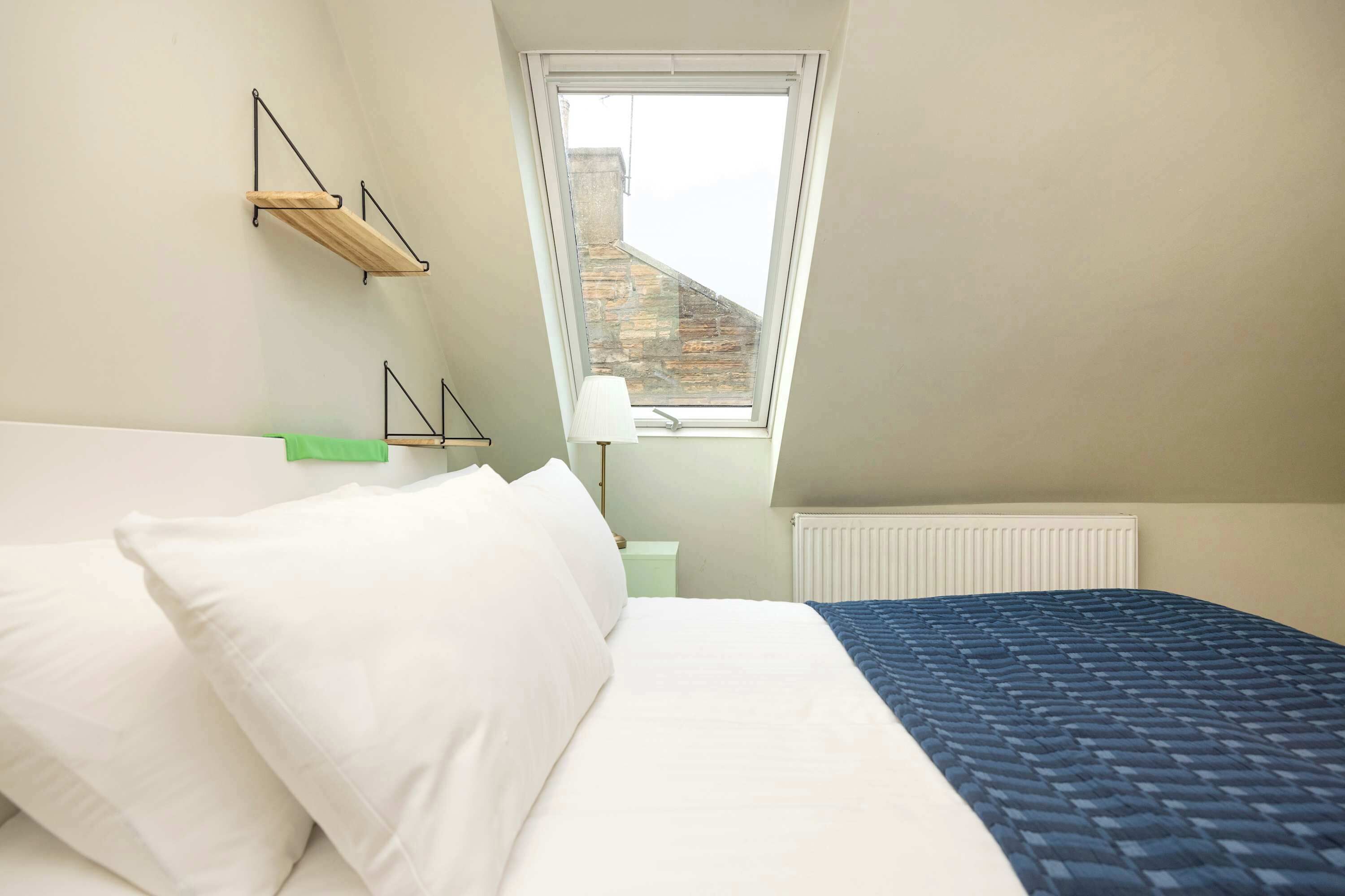 A bedroom with a bed, a window, and a radiator.