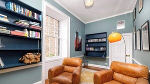 Ein Wohnzimmer mit zwei Ledersesseln, einem Couchtisch und zwei Bücherregalen voller Bücher.