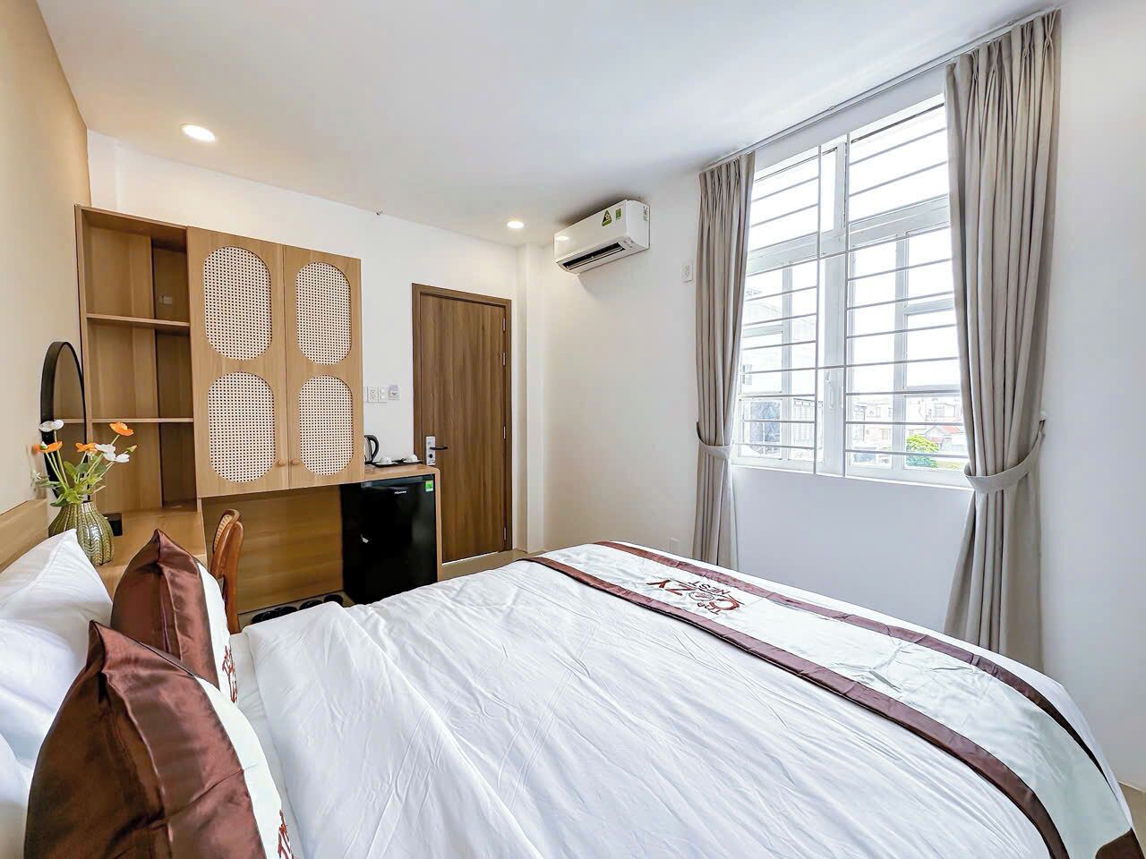 Una habitación de hotel con cama, armario, escritorio y ventana con cortinas.