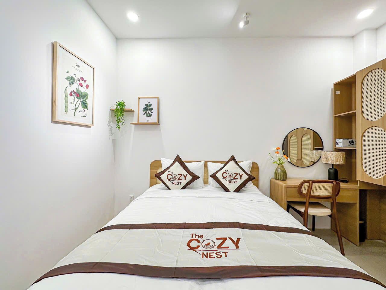 A neatly arranged bedroom with a bed, two pillows, a bedside table, a chair, a desk, and a mirror.