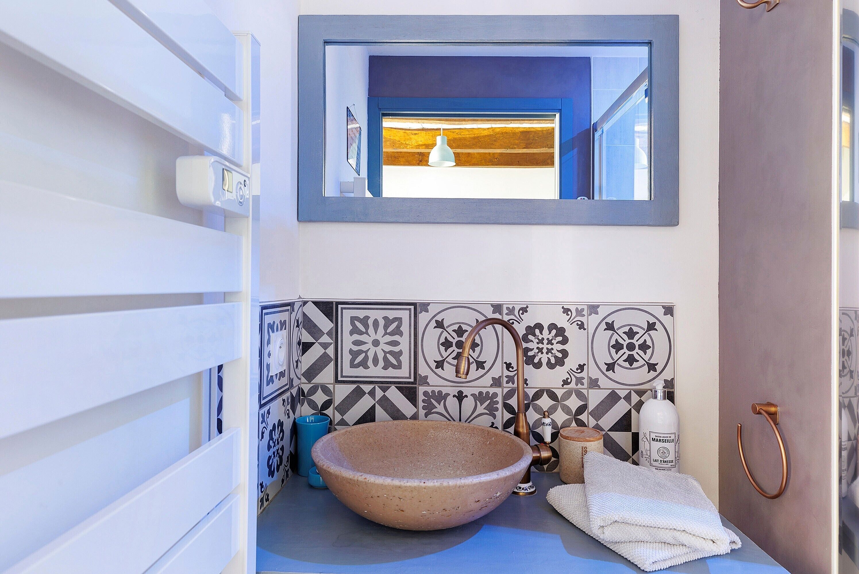 A bathroom with a large, round sink, a towel, a bottle, and a window with a view.