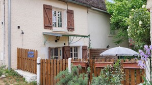 Ein Haus mit Holzzaun, einer Glocke und einem Schild.
