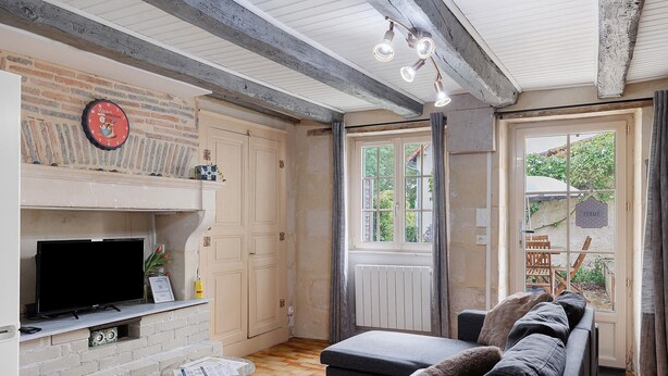 Ein Wohnzimmer mit Kamin, einer Couch, einem Fernseher und einem Fenster mit Vorhängen.