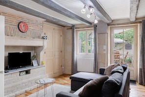 Una sala de estar con chimenea, un sofá, un televisor y una ventana con cortinas.