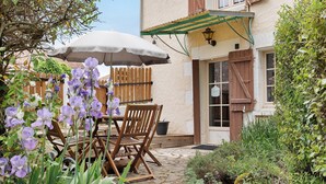 Eine Terrasse mit Tisch und Stühlen, ein Holzzaun und ein Gebäude mit grüner Markise.