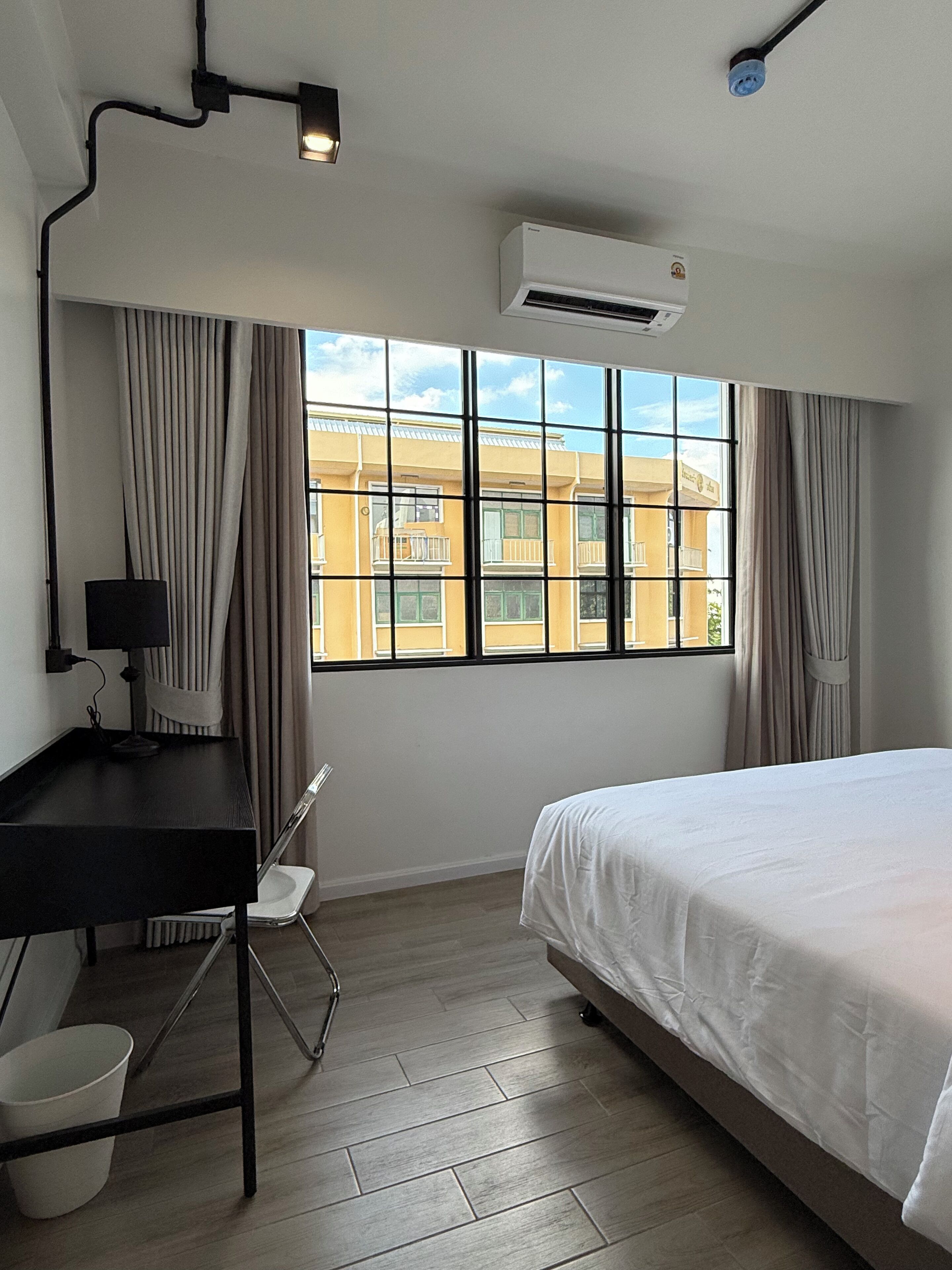 A hotel room with a bed, desk, chair, and a window with curtains.
