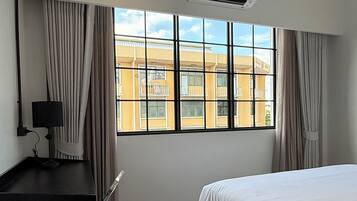 A hotel room with a bed, desk, chair, and a window with curtains.