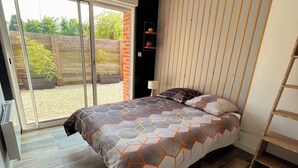 A bedroom with a large bed, a sliding glass door leading to a balcony, and a wooden floor. - Whole House (Wittes)